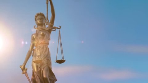 A golden Justitia figure stands against a blue sky with dramatic clouds. The camera zooms out.