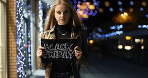 sale, shopping and people concept - Young smiling brunette girl is holding a black friday sign. Black Friday sale. Black Friday sale promotion video. wireless earphones