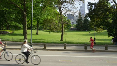NEW YORK - MAY 22, 2015: bicycles in Central Park, bicyclists riding bikes on road with green and trees in background, slow motion 4K Manhattan NY. Central Park is a public park in Manhattan, NYC USA.