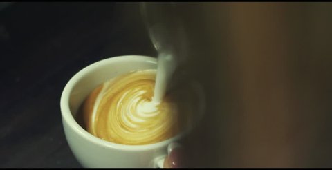 Latte Art drawing heart, milk pouring into coffee slow motion
