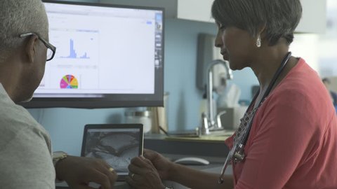 Female doctor explaining reports on tablet computer to patient in clinic