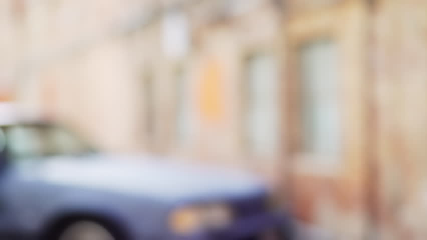 Blurred background plate of an old car in urban alley for compositing. Video backdrop of vehicle outside urban brick building. 