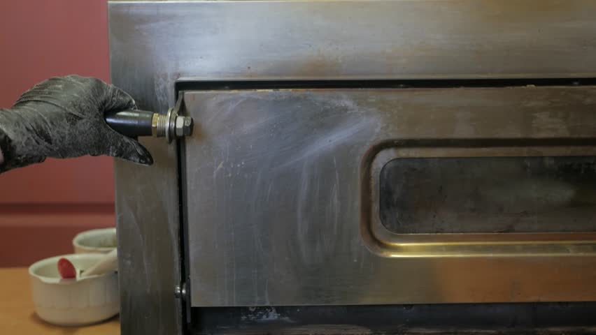 Putting pizza in oven at restaurant kitchen