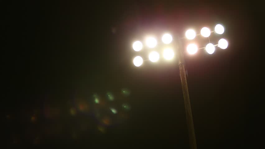 Stadium Lights at High School Football game on Friday Night.  Night Scene, dark with lights and lens flares from lights.