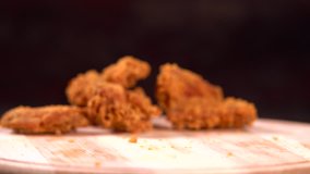 Piece of crumbed fried chicken falling on a wooden board in a low angle close up view