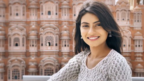 A young Indian female entrepreneur in traditional Kurta smiling looking at the camera. A outdoor mid shot of a beautiful, cute and confident young woman smiles against the historical building 
