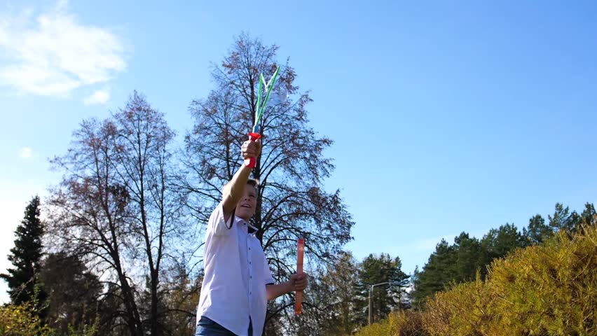 A young guy in the park makes big soap bubbles. Holiday and outdoor entertainment