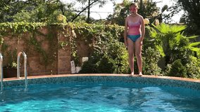 Teenager girl jumping to the swimming pool, slow motion video