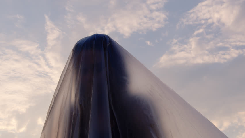 Slow Motion Shot Of A Woman Trapped Underneath Plastic Foil Raising Her Head Looking For Space To Breathe