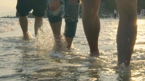 young asian adults walking on beach in sea water, slow motion.