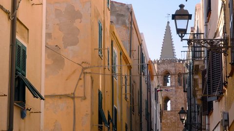 Narrow street in Alghero, Sardinia, Italy, with a campanile in the distance