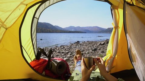 Camping woman lying in tent Close up of Girl feet wearing hiking boots relaxing on vacation POV.