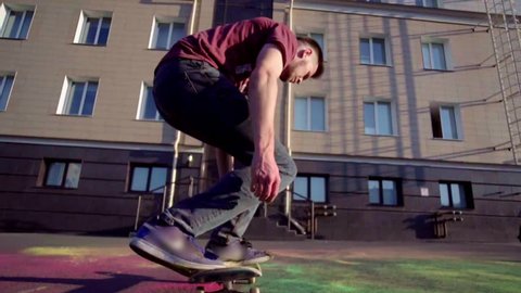 Skateboarder does extreme flip trick with colored powder in slow motion. paints fly in different directions. concept of fun and sports
