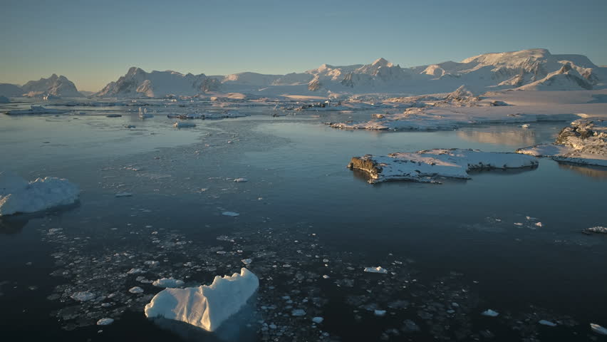 Antarctica aerial view drone flight, over ocean to the mountains. Fast overview the polar ocean, mighty mountains and snow covered Antarctic continent. Time lapse flying over ice water surface. 4k