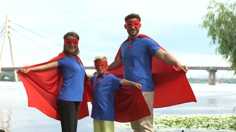 Family in superhero costumes posing for camera, togetherness and outdoor rest