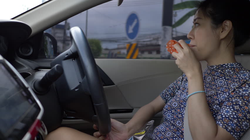 woman eating food with driving car in rush hour