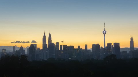 Time lapse: Silhouette of Kuala Lumpur city view during dawn overlooking the city skyline from afar with lushes green in the foreground. Federal Territory, Malaysia. Full HD.