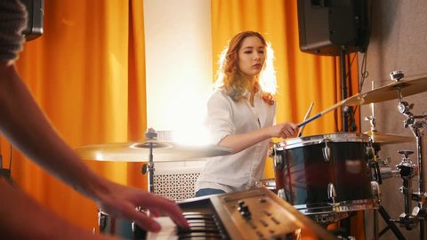 Repetition. Expressive girl drummer and a guy on keyboards. Camera moves from girl to keyboard. Backlight Vídeo Stock
