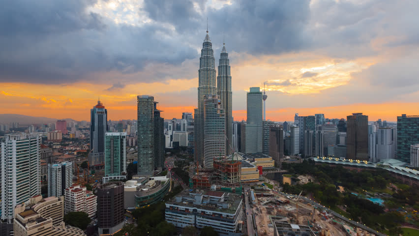 Time lapse: Aerial cityscape view during dusk overlooking the Kuala Lumpur city center skyline and construction area at sunset in Malaysia. Day to night. High Quality 4K Royalty-Free Stock Footage #1017860761