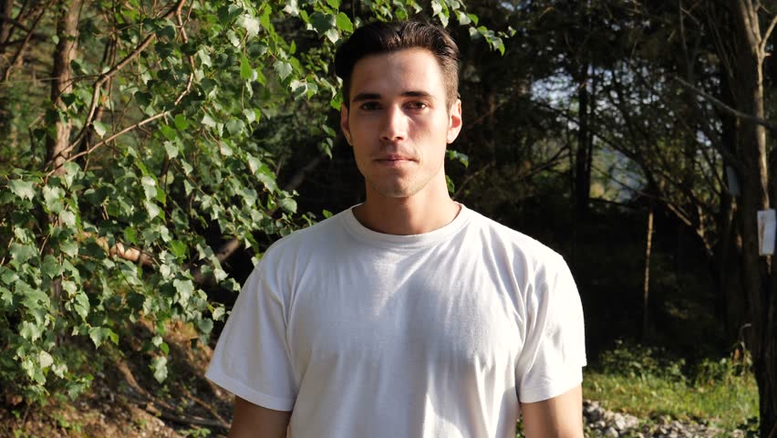 Young handsome man standing in nature, happy, doing thumb up sign with one hand