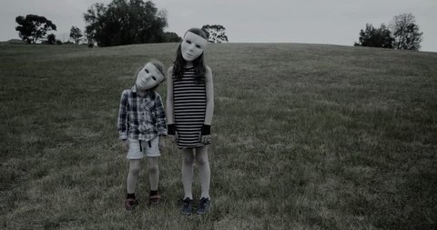 young children wearing a white halloween masks stand creepily and then scarily walk slowly towards the camera