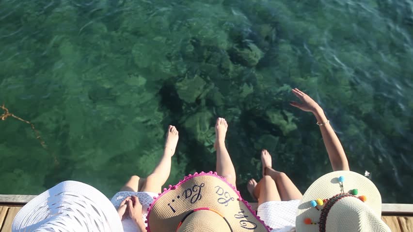 Three girls at a pier with hats at summer