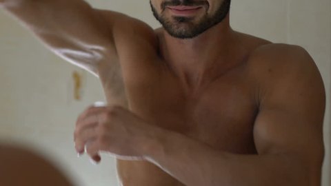 Man applying deodorant on armpit in bathroom, skin care and everyday hygiene