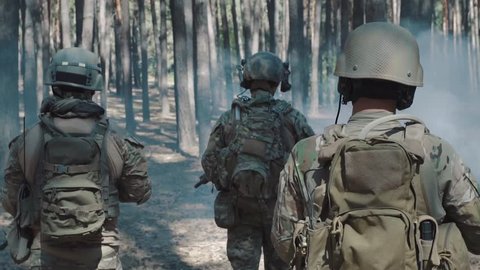 US Army soldiers patrol in a smoky forest