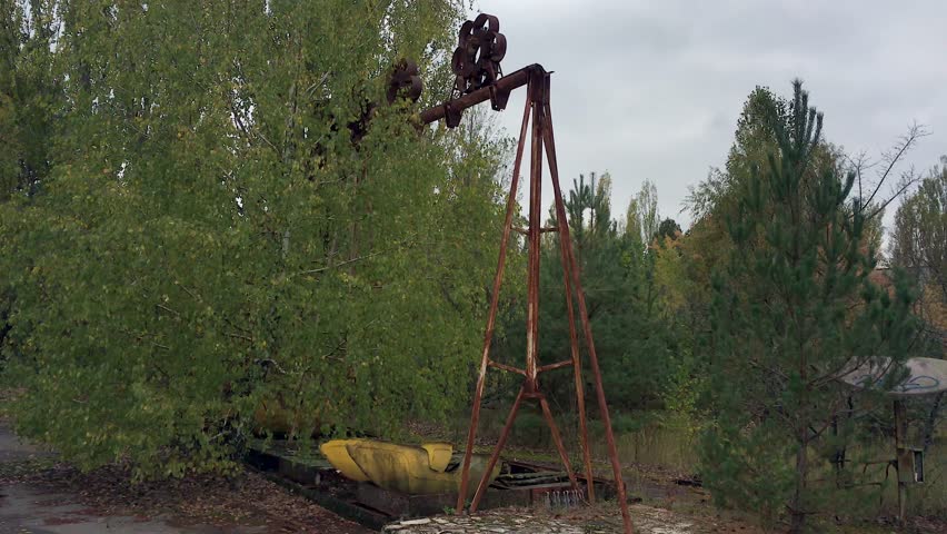 Panning view standing in the middle of the abandoned amusement park of Pripyat, Ukraine on a cold, dark day. Nearby Chernobyl nuclear disaster of 1986 forced permanent evacuation of town residents.