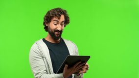 young crazy man with a touch screen tablet against green chroma key background