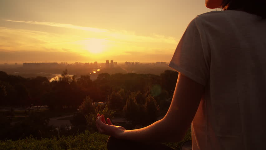 woman meditating and observing the sunset sky. On the background city landscape. She wears a white T-shirt, has dark hair Royalty-Free Stock Footage #1017904951