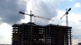 Time lapse of a construction site.Huge cranes lifting construction materials.Dark and white clouds hanging under the clear blue sky.Great for commercials related to construction sites, real estate
