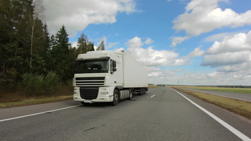 White semi-truck with cargo trailer moving on highway Royalty-Free Stock Footage #1017906103