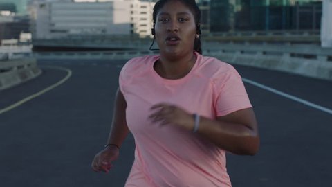 overweight woman running exercising running weight loss challenge jogging in urban city at sunset wearing earphones