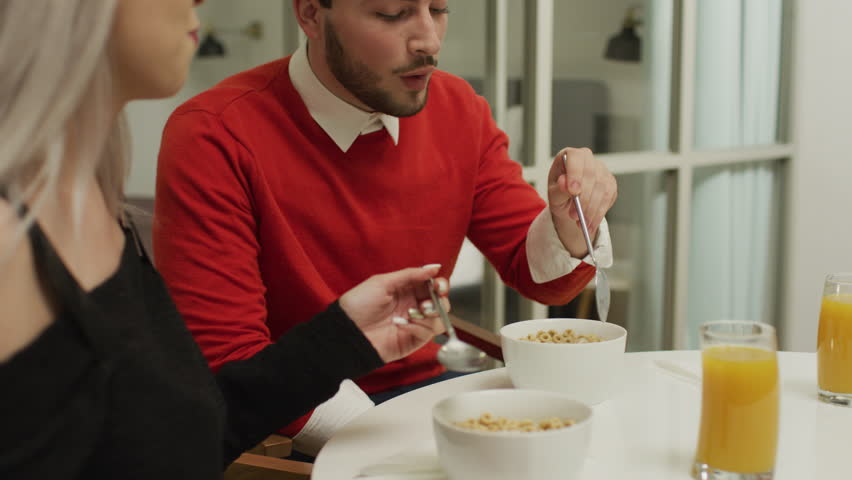 Young couple eating breakfast at home.