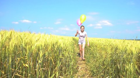 Happy teen female with balloons having fun in field