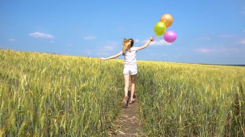 Female with balloons rinning in field