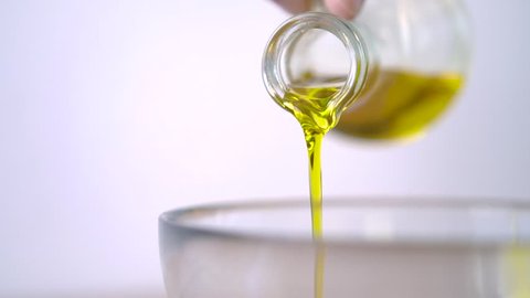 Pouring Virgin Olive Oil in glass bowl for salad in kitchen