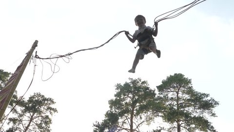 Boy jumping with ropes. Rope jumping background. Game for children. Extreme games. Extreme sport for children. Jumping high in the sky.