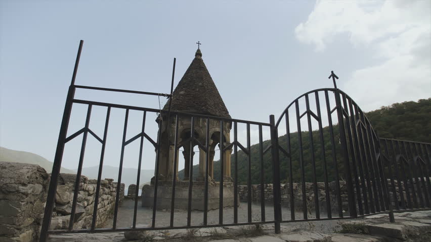 The bell tower in old mountain Orthodox Church surrounded by the stone Ananuri fortress. Historical buildings in highland part of Georgia