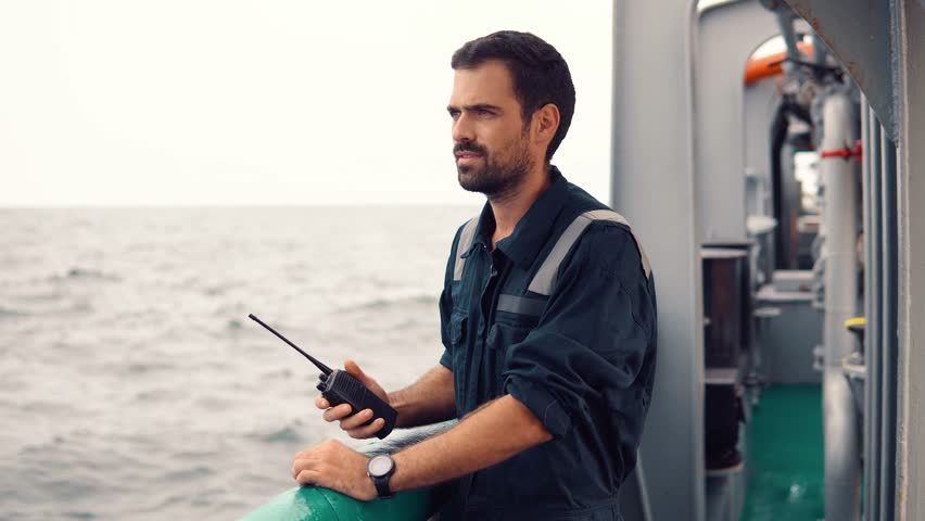 Marine Deck Officer or Chief mate on deck of vessel or ship . He holds VHF walkie-talkie radio in hands. Ship communication Royalty-Free Stock Footage #1017933244