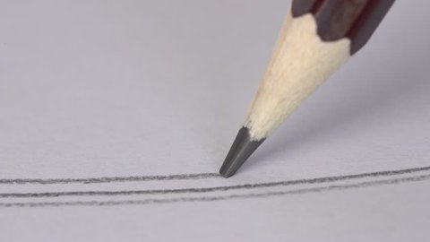 Artist hand drawing a flat gray line with a graphite wooden pencil on white paper. Close up, macro, 4k