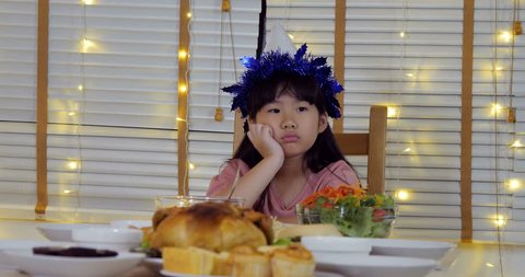 Little girl waiting father mother or friend comes to dinner with boring emotion. Asian little girl lonely in party at home.