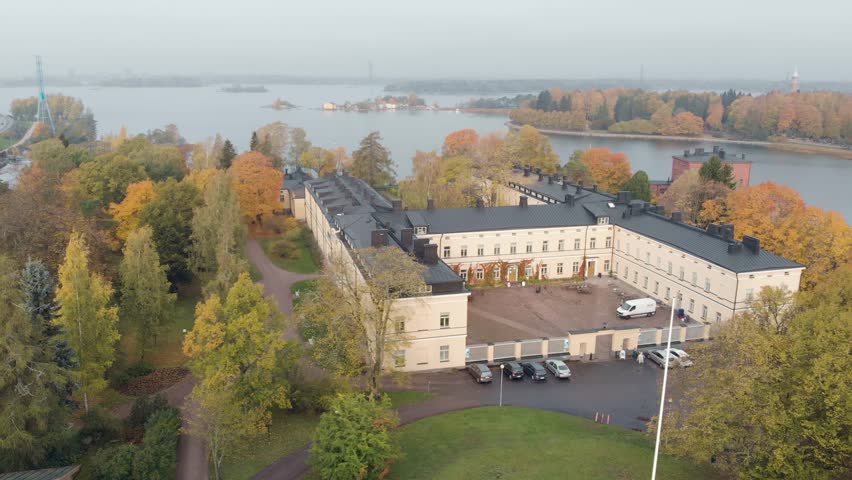 Aerial view of Lapinlahti Hotel and Hospital Helsinki Finland. Autumn with yellow and green colorful trees. Cloudy and calm daytime scene. Drone flying sideways and panning.