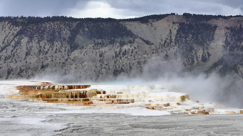 Steam, colorful rocks and water seen around volcanic landscape at Mammoth Springs.
