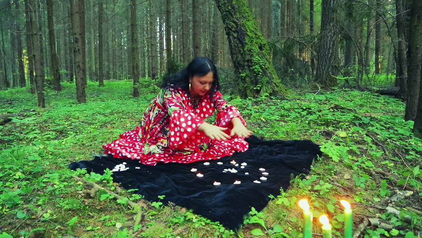 A young gypsy woman in the forest performs magical movements with her hands over burning candles. Royalty-Free Stock Footage #1017955945