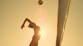 SLOW MOTION, LOW ANGLE, CLOSE UP, SUN FLARE: Athletic girl playing beach volleyball jumps in the air and strikes the ball over the net on a beautiful summer evening. Caucasian woman score a point. - Powered by Shutterstock - Get 15% off with code: PIKWIZARD15