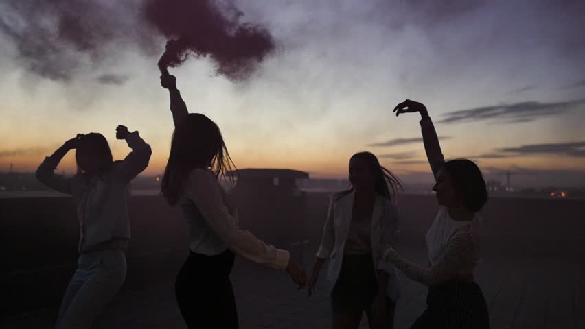 Silhouettes of young people and dancing with raised arms to the music played by dj at rooftop party during beautiful city sunset | Shutterstock HD Video #1017959014