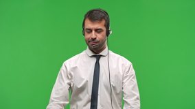 Handsome telemarketer man smiling with a happy and pleasant expression while pointing mouth and face with fingers on green screen chroma key