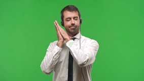 Handsome telemarketer man making sleep gesture. Adorable and sweet expression on green screen chroma key